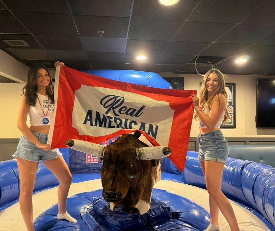 2 Girls Holding a Flag over Mechanical Bull at Happy Valley Live
